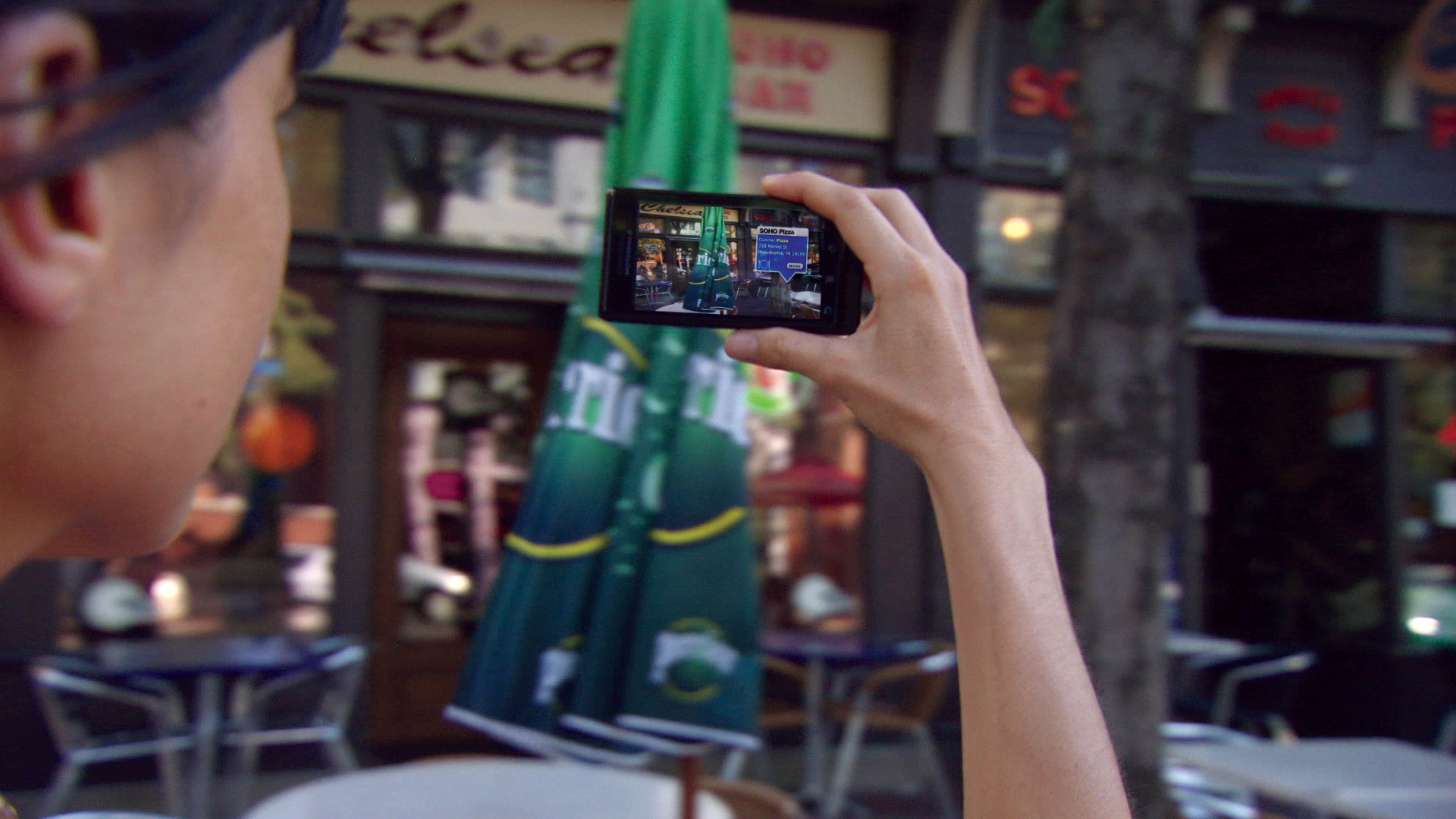 Young woman looking through a phone at a real-time data overlay of the surroundings.